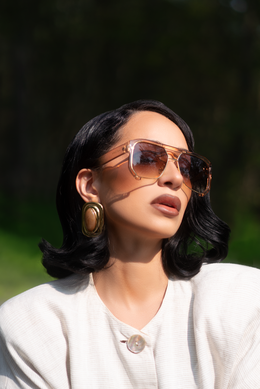 Woman wearing sunglasses and a white top outdoors with a blurred background