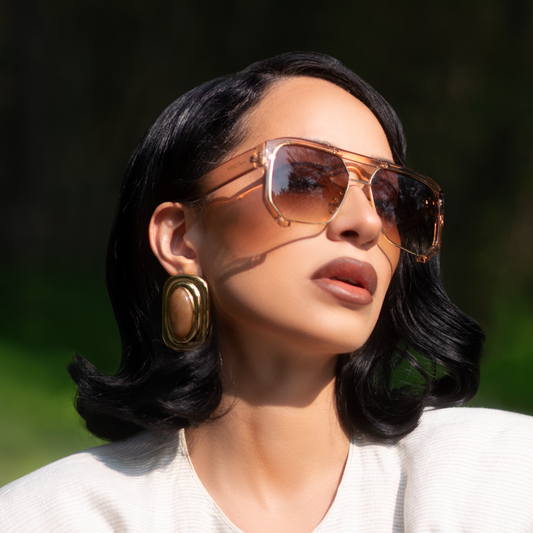 Woman wearing sunglasses and a white top outdoors with a blurred background