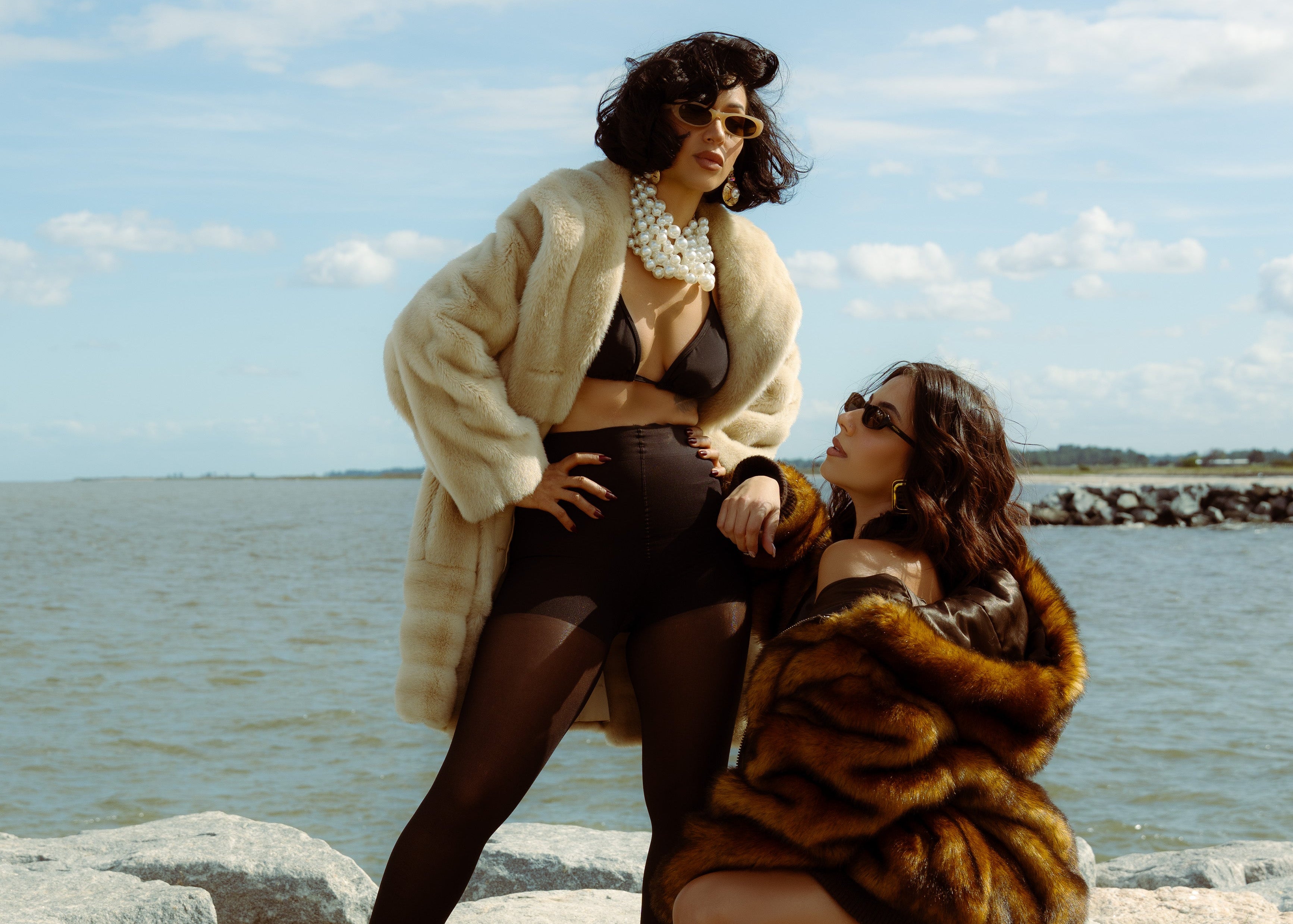 Two women in fur coats by a body of water on a sunny day wearing 1980nine HAZEL sunglasses