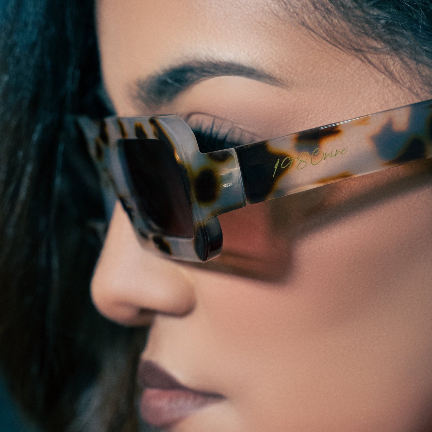 Close-up of a person wearing tortoiseshell sunglasses with a blurred background
