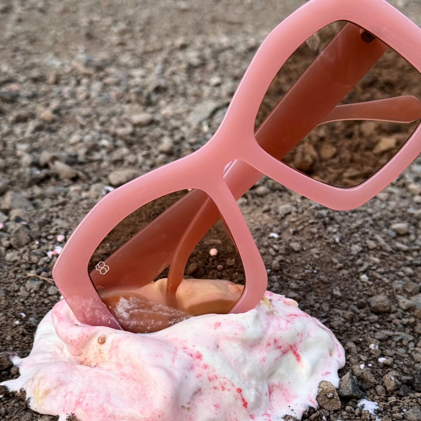 Pink sunglasses in ice-cream laying on cement.