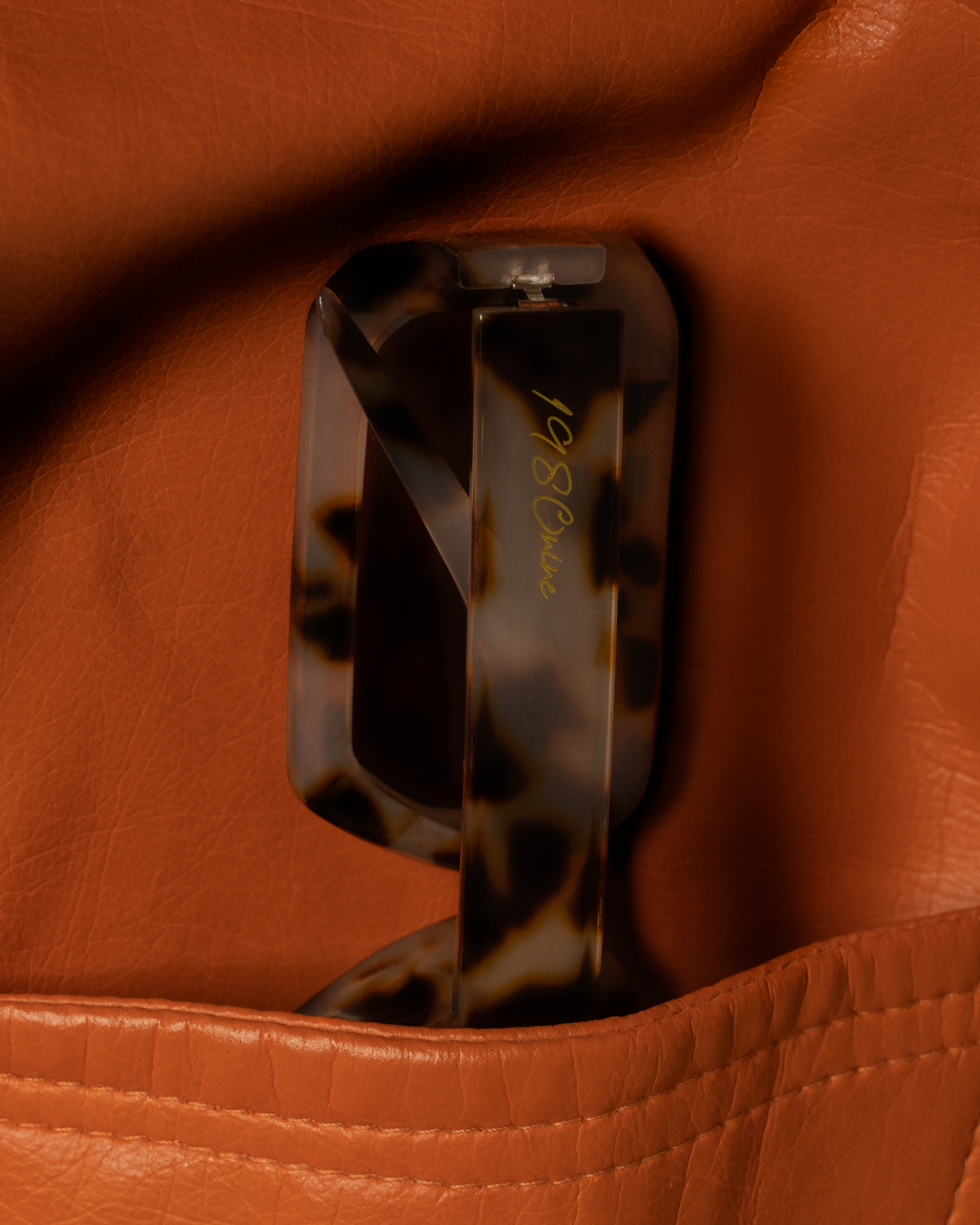 Close-up of a tortoiseshell sunglasses on a brown leather surface