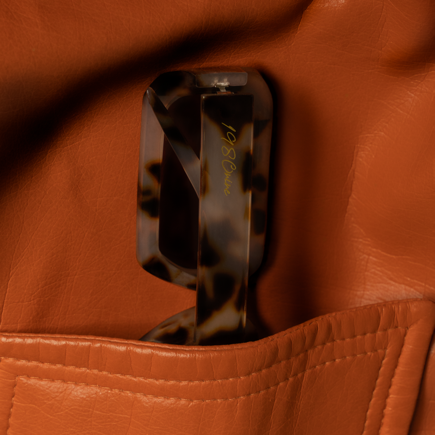 Close-up of a tortoiseshell clutch on a brown leather surface