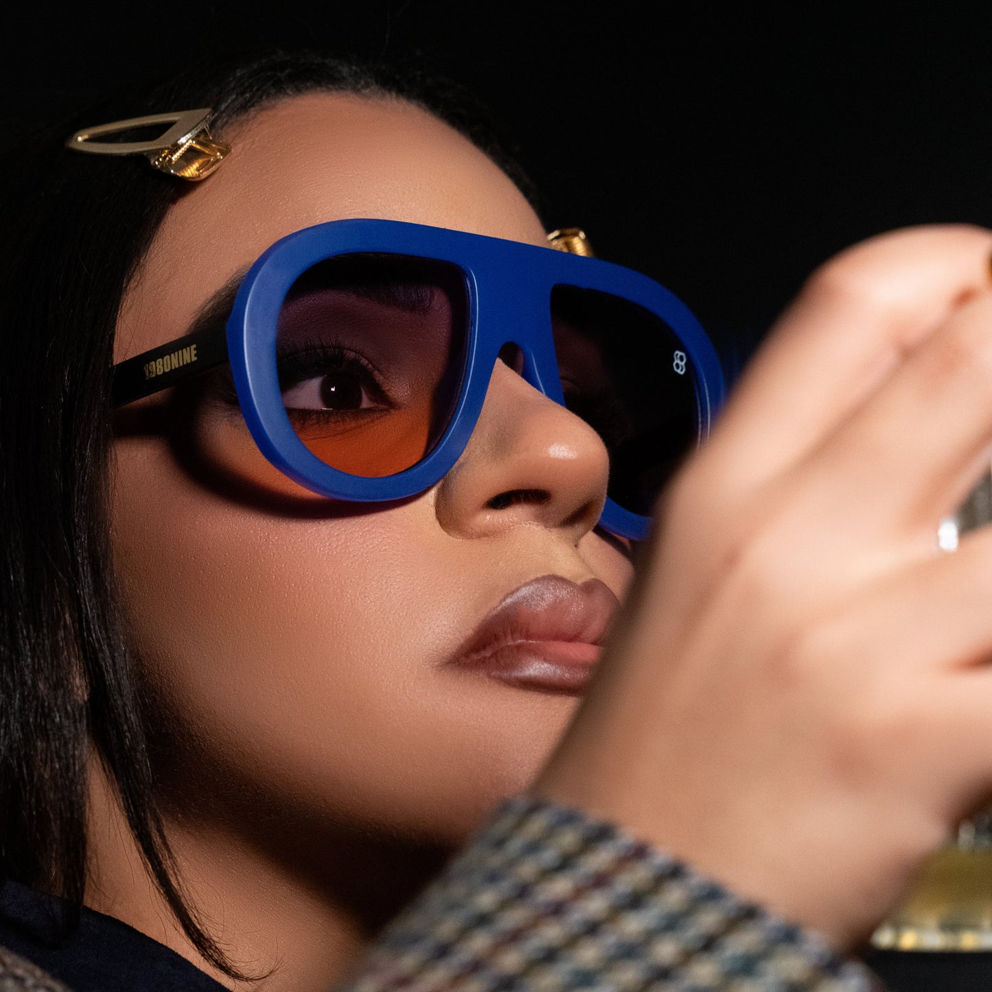 Oversized oval sunglasses with thick frames, available in green with yellow lenses, black with dark lenses, and blue with purple-tinted lenses. Wide, bold arms.