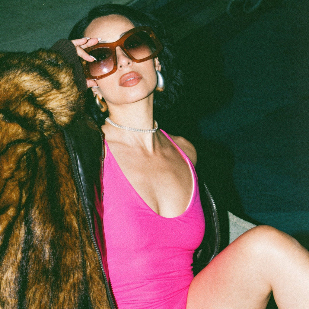 Person wearing a pink swimsuit and fur coat indoors