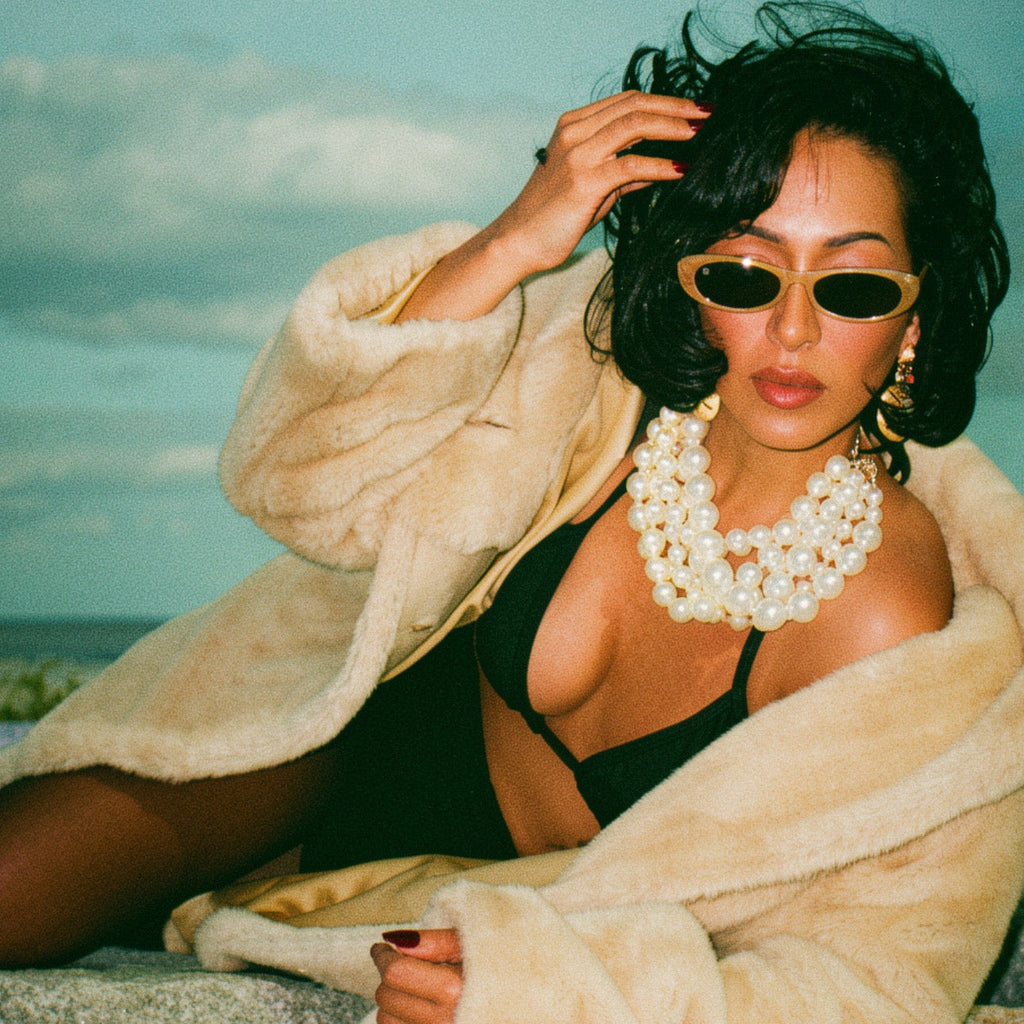 Woman in a robe and sunglasses sitting on a rock with a scenic background
