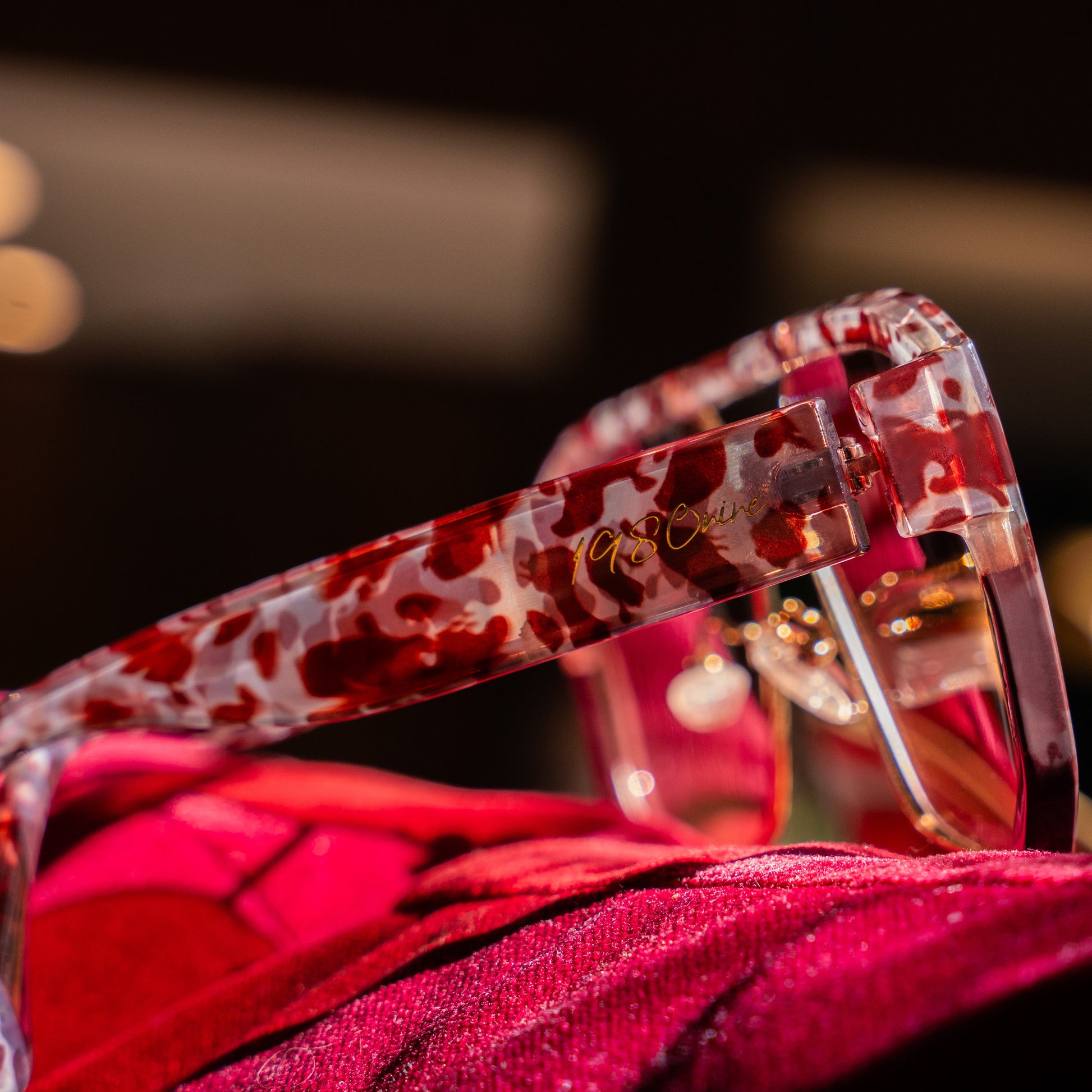Red 1980nine sunglasses with a patterned frame on a dark background