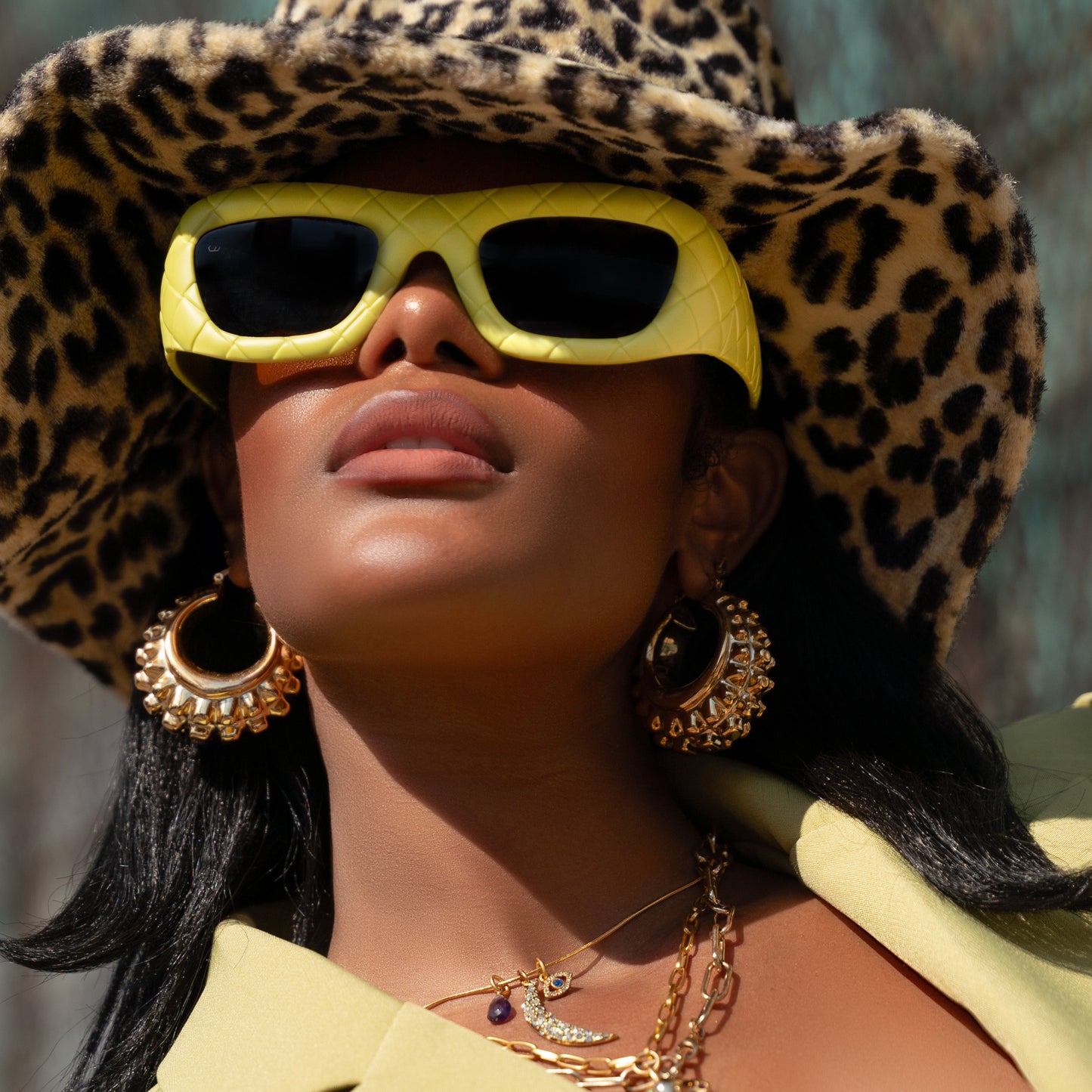 Model wearing oversized yellow quilted chunky frame sunglasses with rectangular lenses.