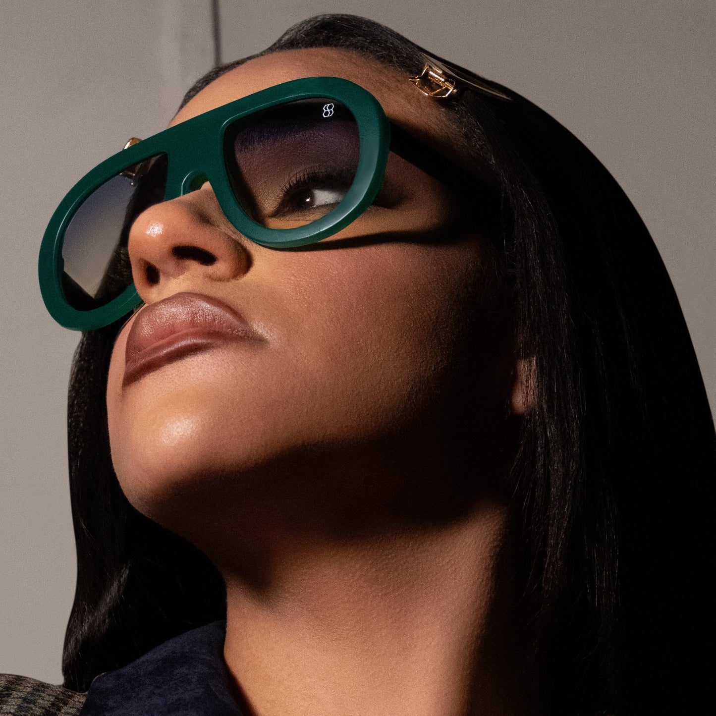 Oversized oval sunglasses with thick frames, available in green with yellow lenses, black with dark lenses, and blue with purple-tinted lenses. Wide, bold arms.
