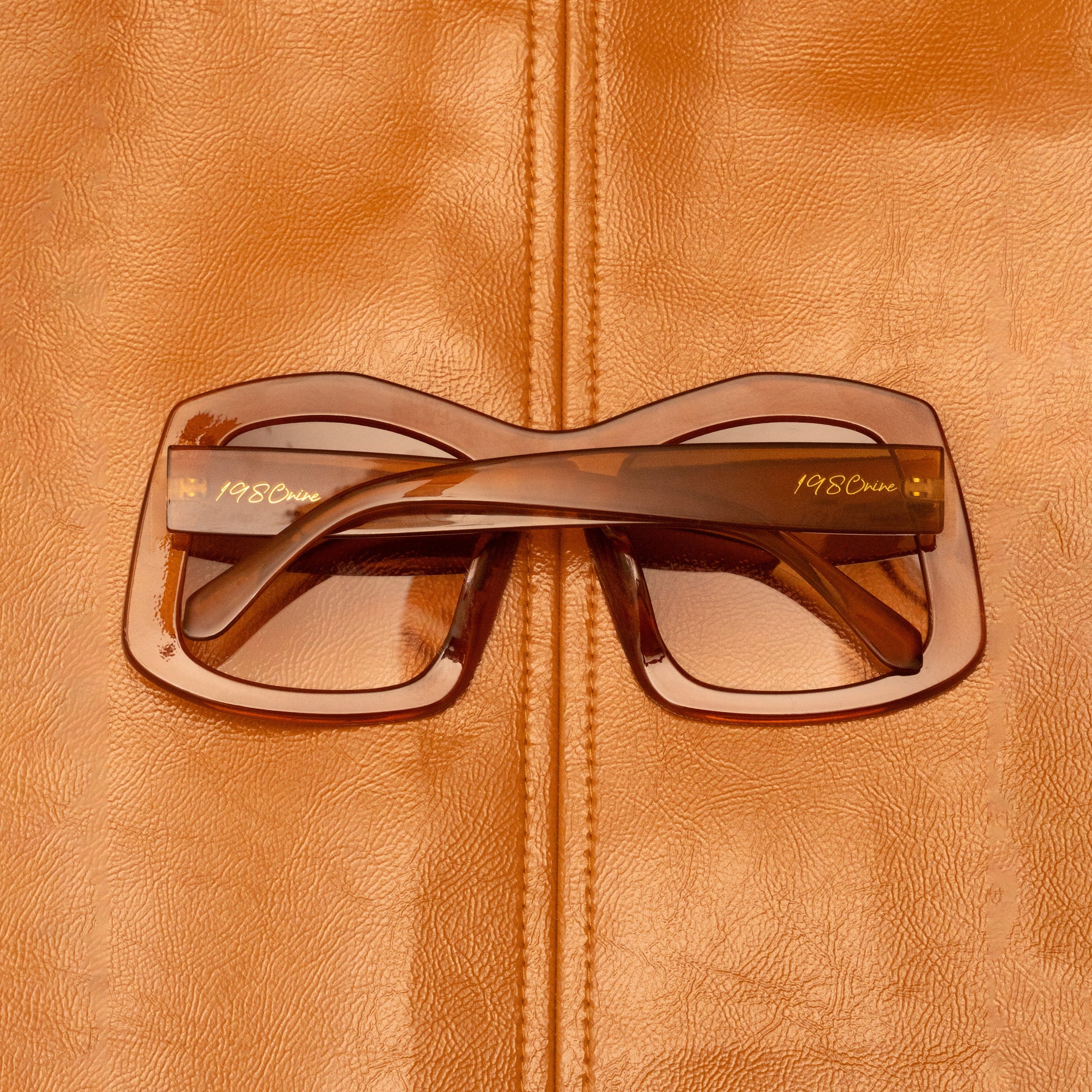 1980nine Sunglasses with a brown frame on a brown leather surface
