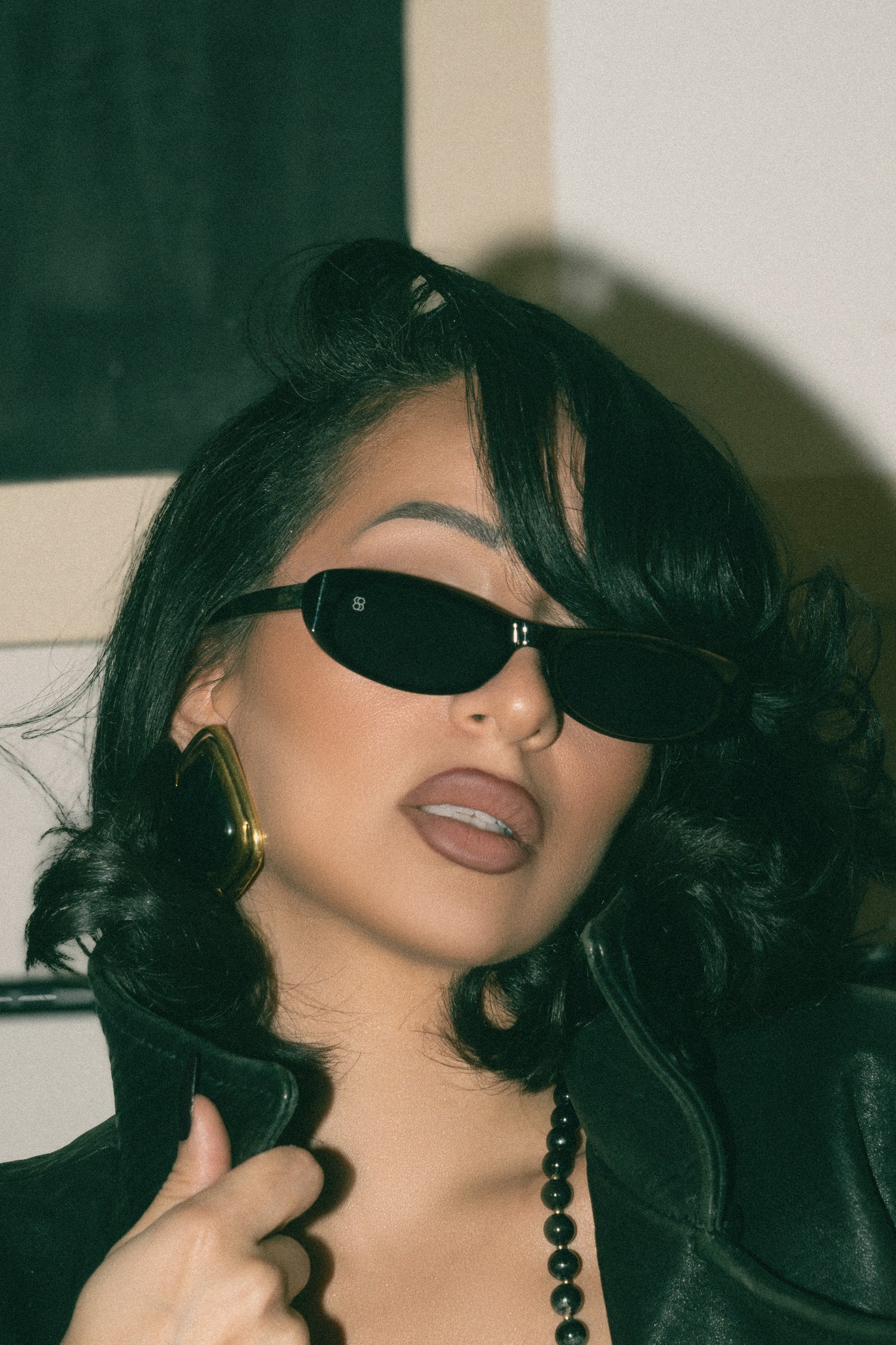 Person wearing sunglasses and a black outfit with a blurred background