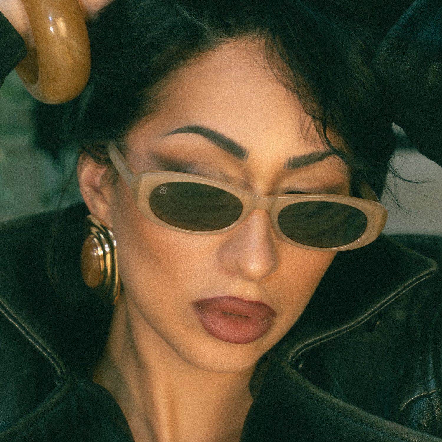 Person wearing sunglasses and a dark coat with a blurred background