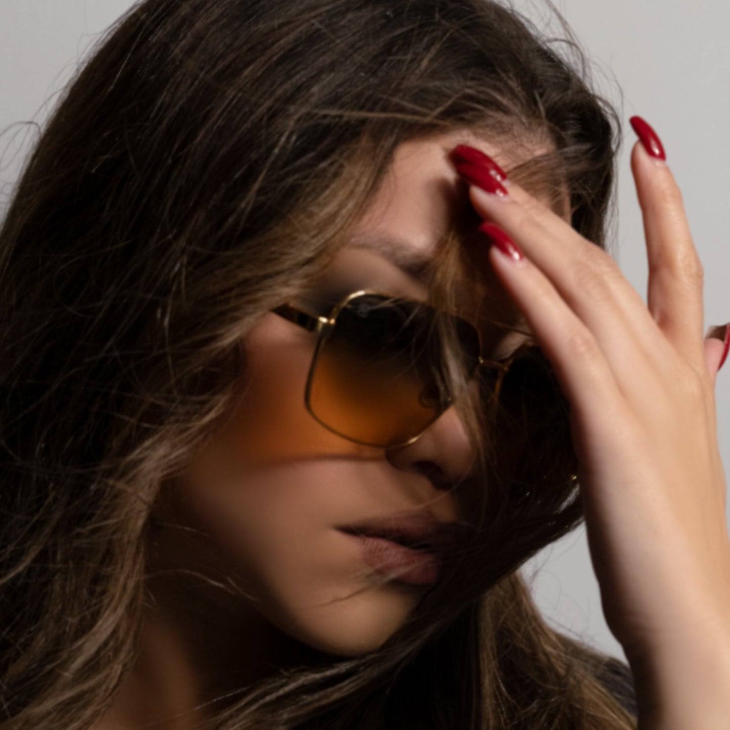 Model wearing gold metal aviator sunglasses with amber gradient lenses and sleek metal frame.