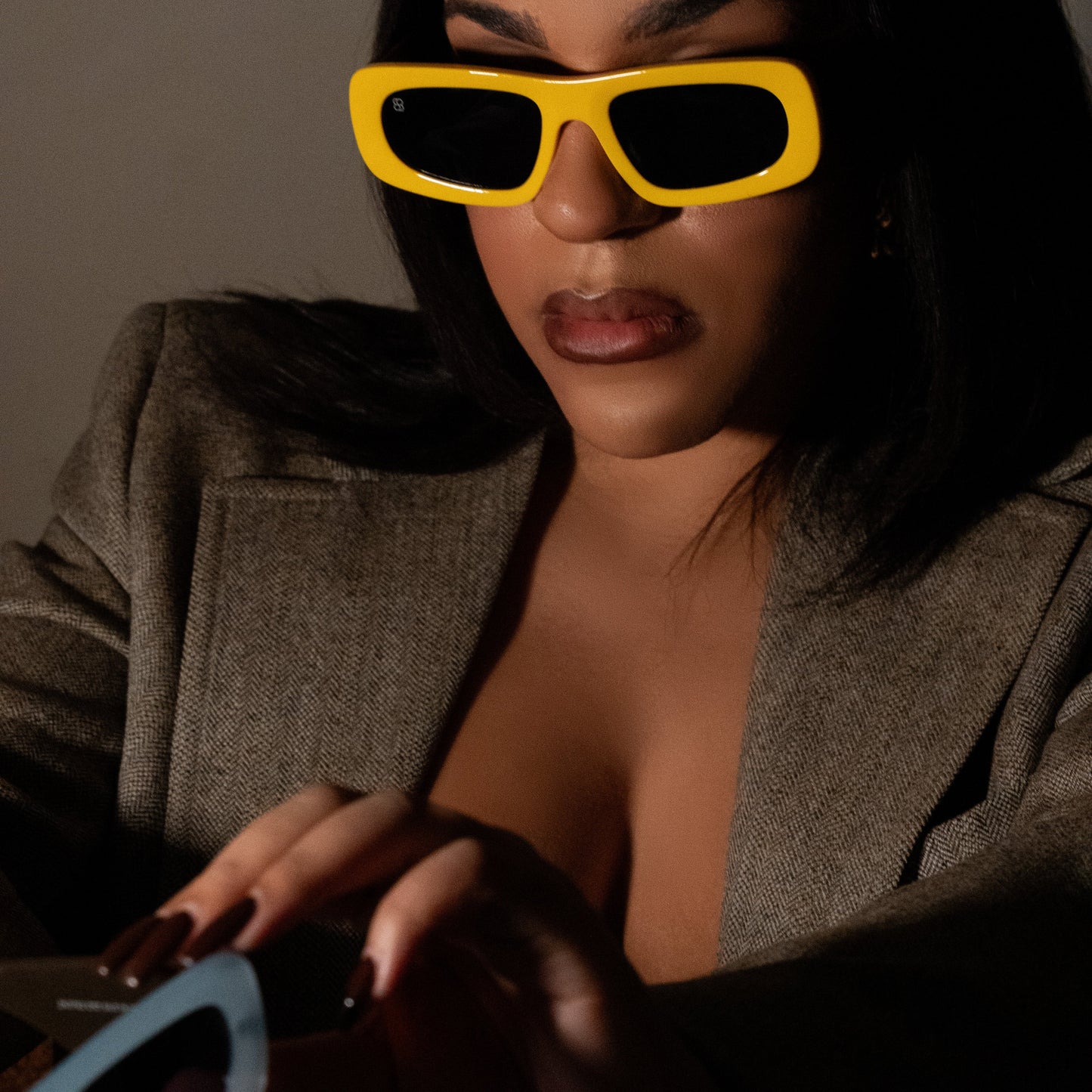 Model wearing bold yellow rectangular sunglasses with thick sculpted rims and dark tinted lenses.